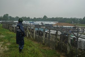 Myanmar security force member garuds Myanmar-Bangladesh border fence next to makeshift camps of Rohingya in No man's land, September 2018