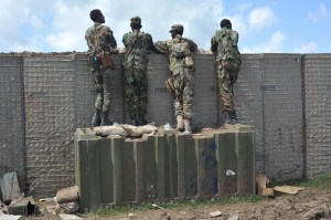 Somali soldiers stand on a platform overlooking a wall.