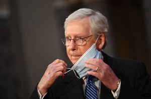 Senate Majority Leader Mitch McConnell, R-Ky., adjusts his face mask as he participates in a mock swearing-in for the 117th Congress with Vice President Mike Pence in the Old Senate Chambers at the U.S.