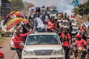 Bobi Wine rides on the roof of a car in Uganda with his supporters.