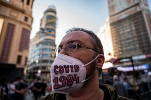 ​A man in Madrid, Spain, wearing a protective face mask with the letters "covid 1984", alluding to George Orwell's novel, protesting against new normality and New World Order conspiracy theory during the COVID-19 crisis. Photo: Marcos del Mazo/LightRocket