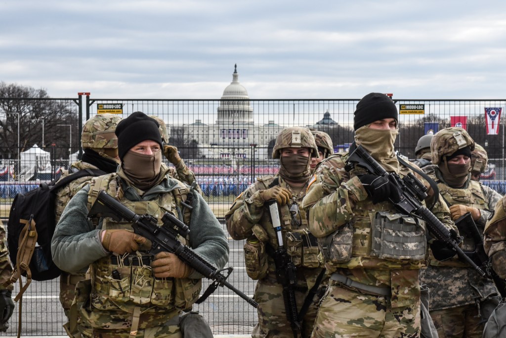 National Guard troops holding rifles stand watch over the Capitol building in Washington, DC