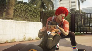 Screenshot from Hitman 2, Agent 47, wearing a clown outfit including a bright red wig and clown nose, chokes out a military officer.