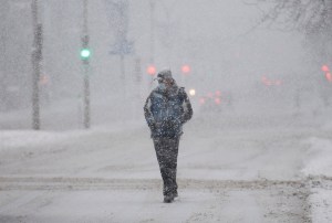 A man wears a face mask as he walks along a street during a snowstorm in Montreal, Saturday, January 16, 2021.