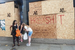 A group of young people stand next to a sign that reads "Brexshit".