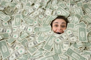 A person is smiling from under a pile of money.