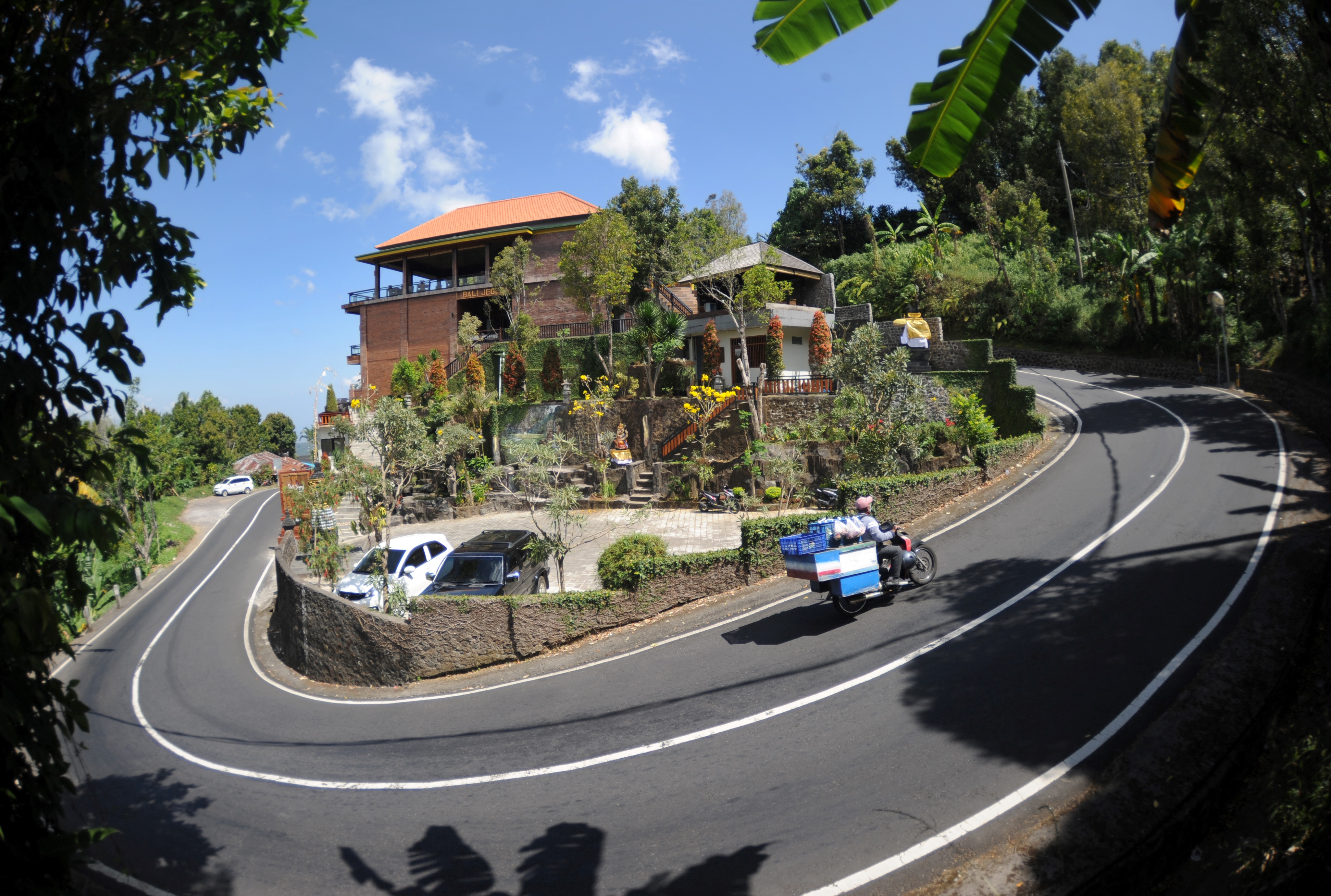 A motorist commutes past a villa in Bali's Munduk village, which has seen a downturn in tourists due to ongoing COVID-19 travel restrictions (PHOTO: AFP / SONNY TUMBELAKA)