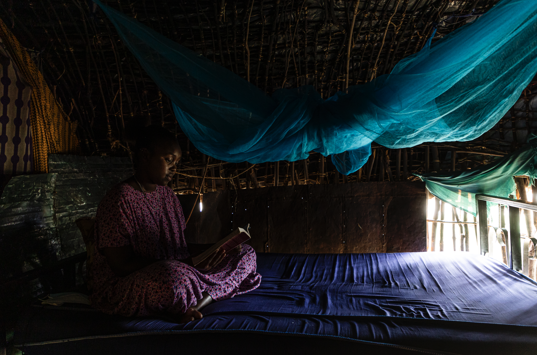 A young woman sits on a bed.