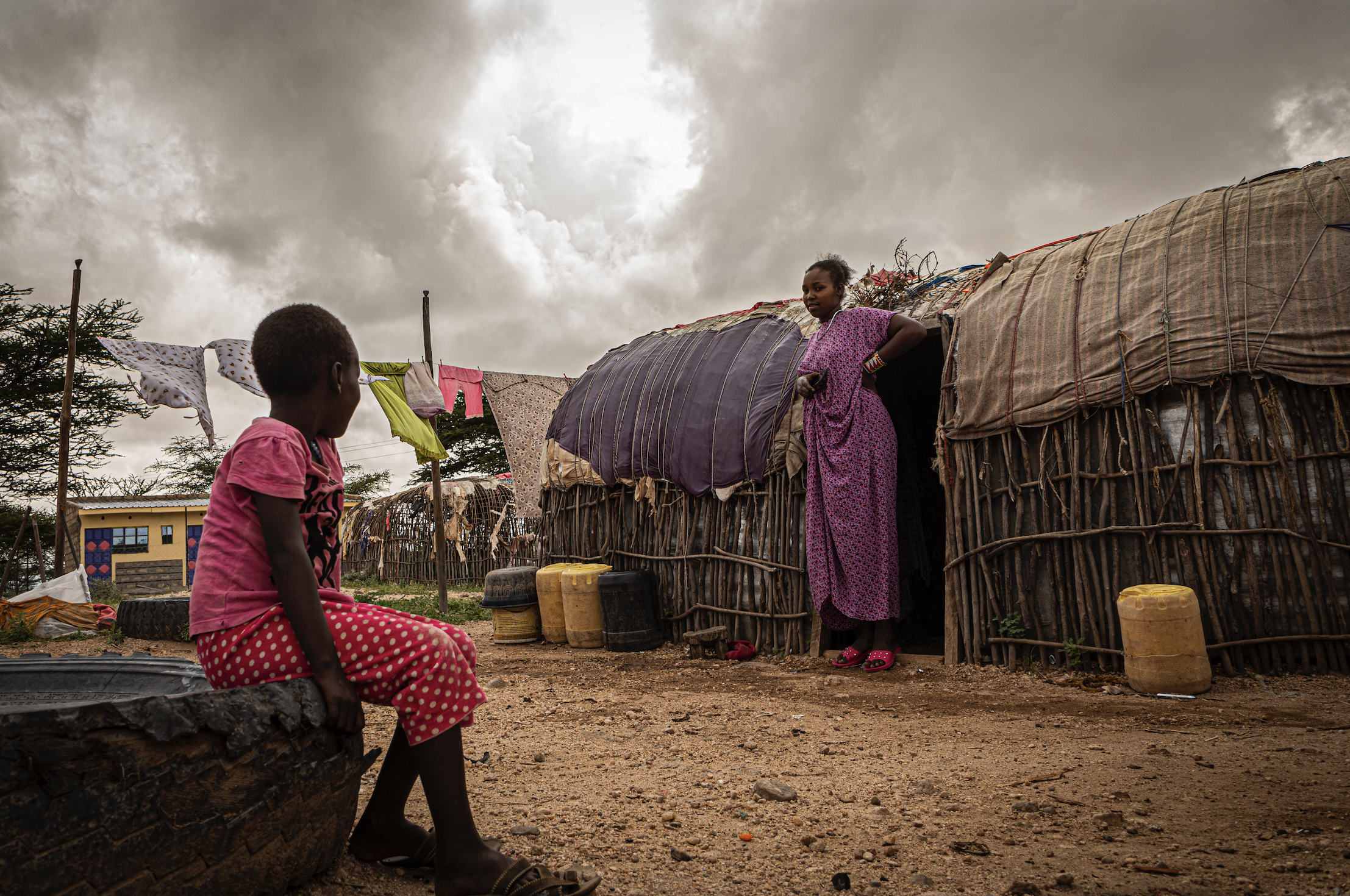 Two women sit outside their house.