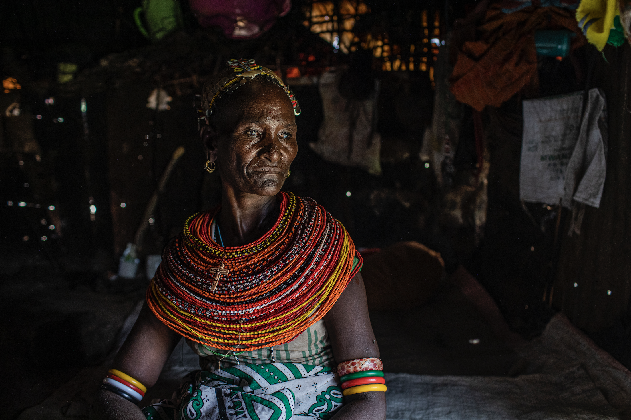 A woman sits inside wearing colorful necklaces.