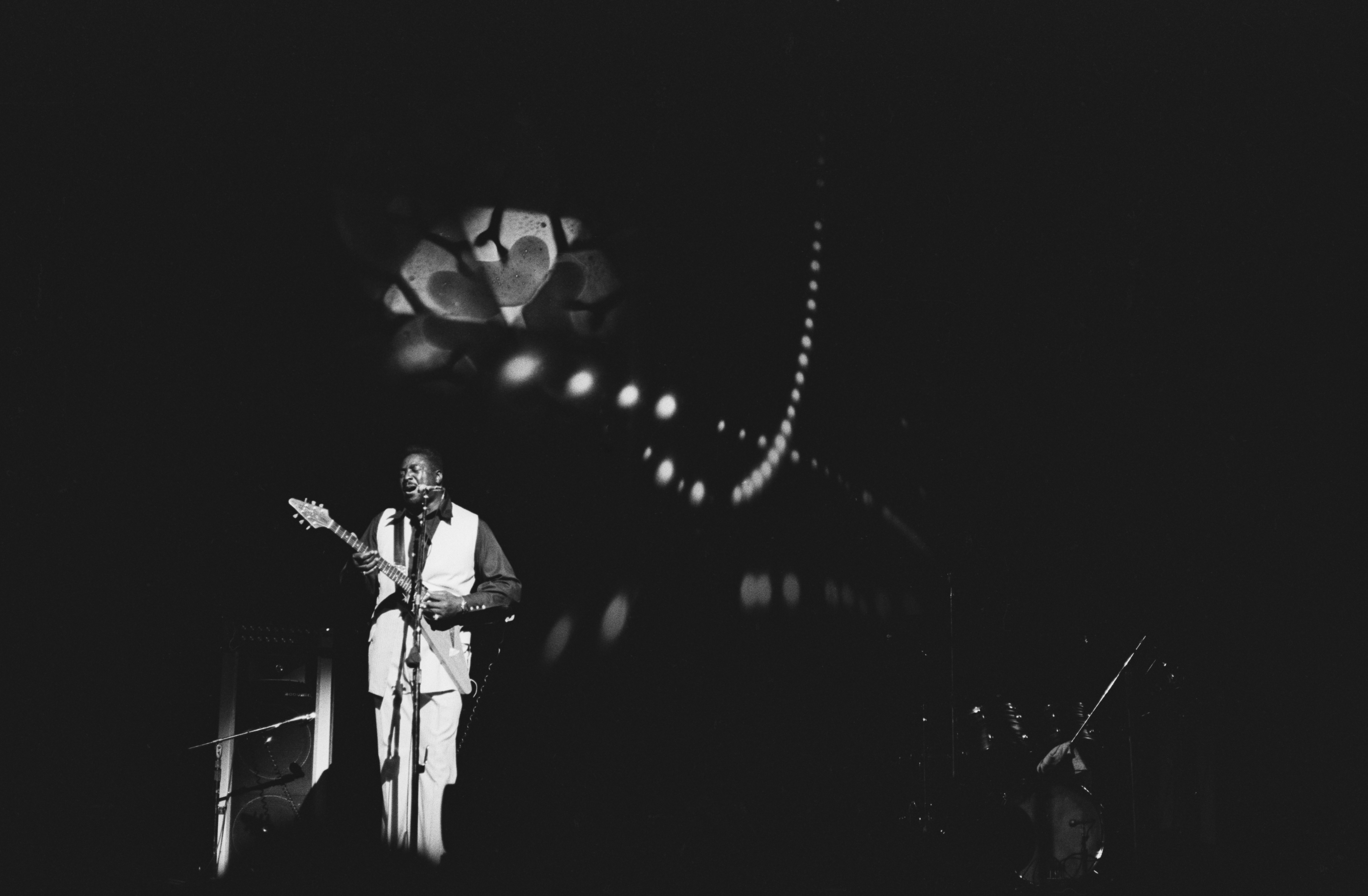 Guitarist Albert King in a black and white photo on a darkened stage.