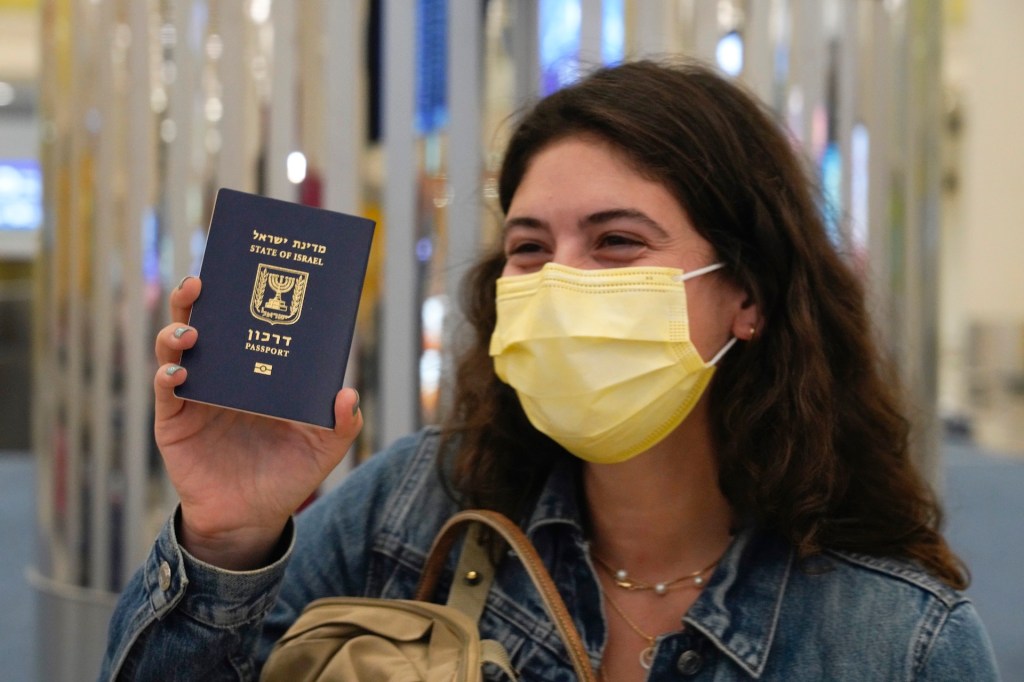 An Israeli passenger from a flyDubai flight from Tel Aviv, Israel, waves her Israeli passport on arrival at Dubai International Airport's Terminal 3 in Dubai, United Arab Emirates, Thursday, Nov. 26, 2020.