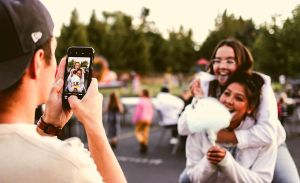 One friend takes a photo or video of two other friends.