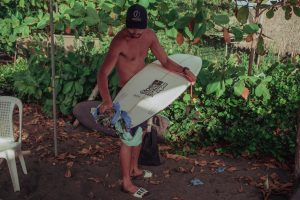 Bryan Pérez limpia su tabla después de su participación en un campeonato de surf en las costas de El Salvador. Foto: Carlos Barrera