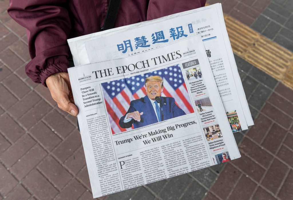 A woman distributes the multi-language newspapers The Epoch Times newspaper featuring on its front cover the former US President Donald J. Trump in Hong Kong in November.