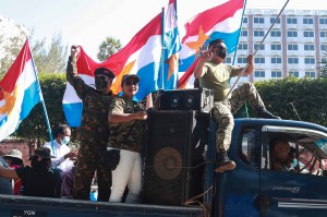 Supporters on a car wave national and military flags Tuesday, Feb. 2, 2021, in Yangon, Myanmar. Hundreds of members of Myanmar's Parliament remained confined inside their government housing in the country's capital on Tuesday, a day after the military sta