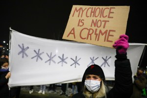 A woman holds a sign that says "My Choice is Not a Crime"