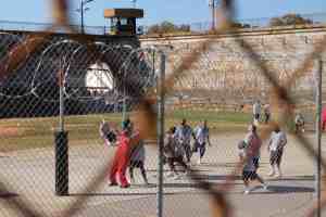 Individuals play basketball inside of a prison.