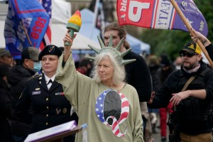 A person dressed as Lady Liberty wears a shirt with the letter Q, referring to QAnon, as protesters take part in a protest, Wednesday, Jan. 6, 2021, at the Capitol in Olympia, Wash., against the counting of electoral votes in Washington, DC, affirming Pre