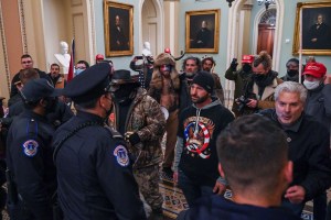 A man wearing a QAnon sweatshirt faces US Capitol police officers as they try to stop supporters of US President Donald Trump from entering the Capitol on January 6, 2021, in Washington, DC.