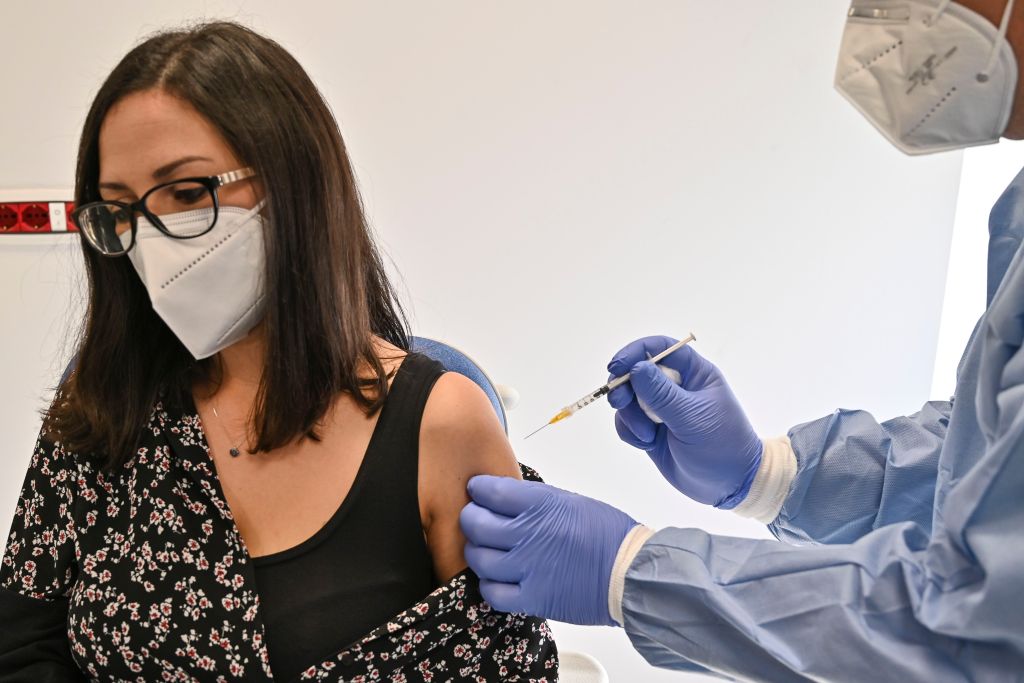 A doctor wearing a mask receives a COVID-19 vaccine