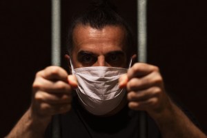 man with mask behind bars