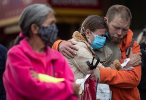 A woman and man embrace while listening to people speak about loved ones during a memorial to remember victims of illicit drug overdose deaths on International Overdose Awareness Day, in the Downtown Eastside of Vancouver, on Monday, August 31, 2020.