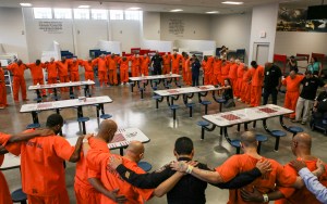 In this Thursday, July 25, 2019 photo, prisoners embrace for a prayer inside the Harris County Joint Processing Center in Houston.