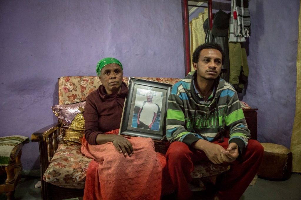 A woman and man sit on a couch holding a photograph.