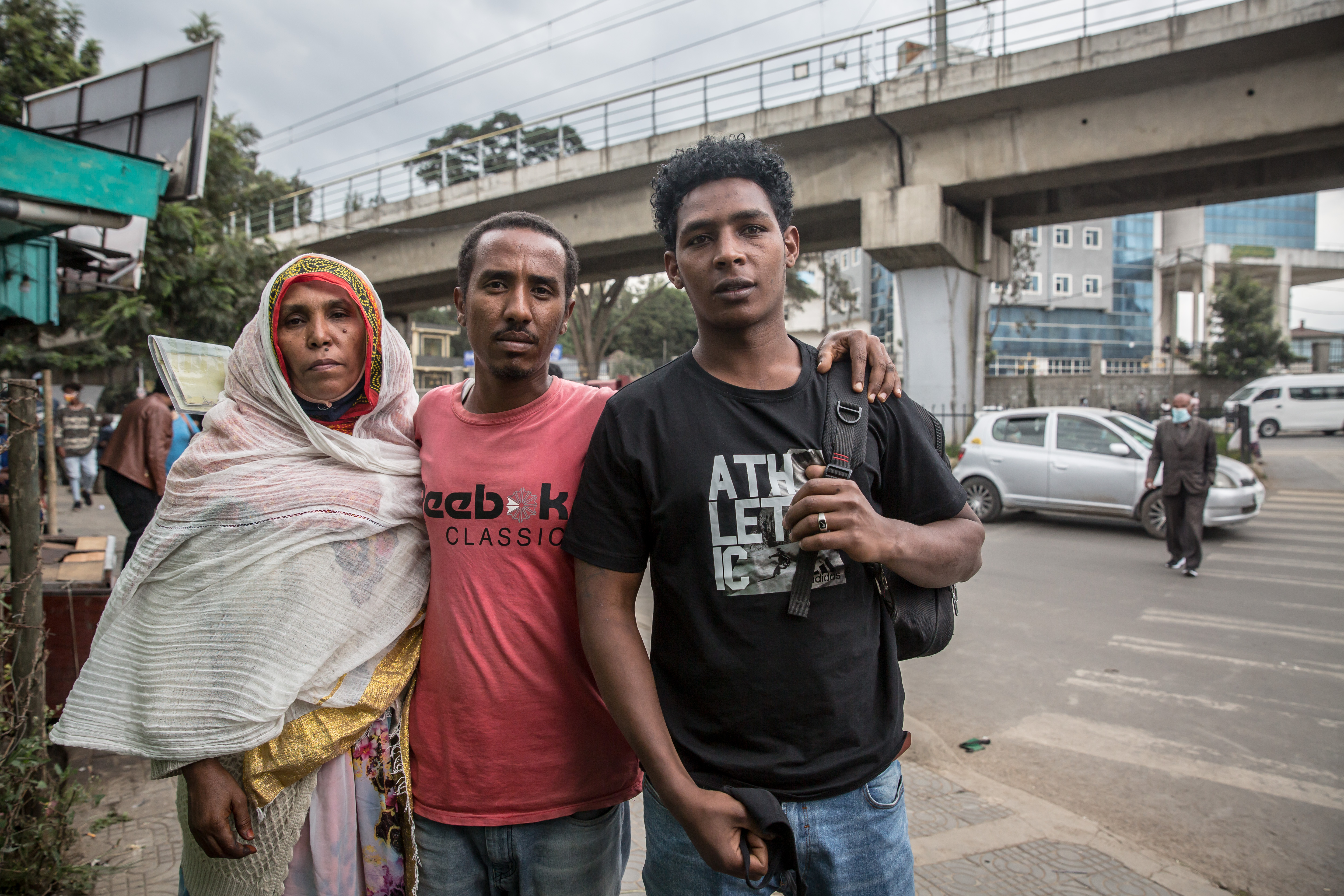 Three people stand on a street.