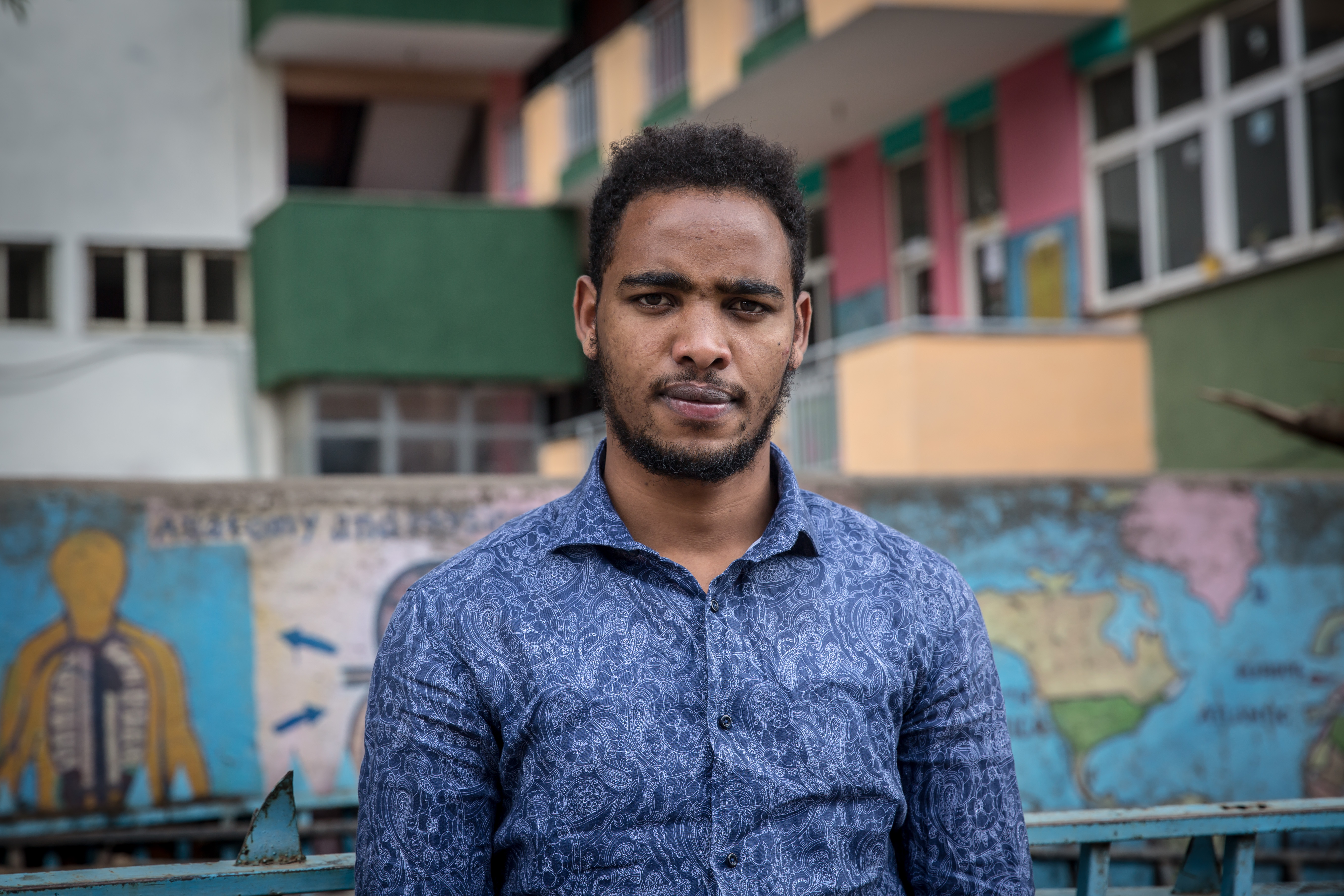 A portrait of a man against the backdrop of colorful apartment buildings.