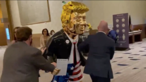 Screenshot of video showing golden Trump statue being brought in to CPAC on Thursday, February, 26, 2021. (Twitter/Will Turton)​