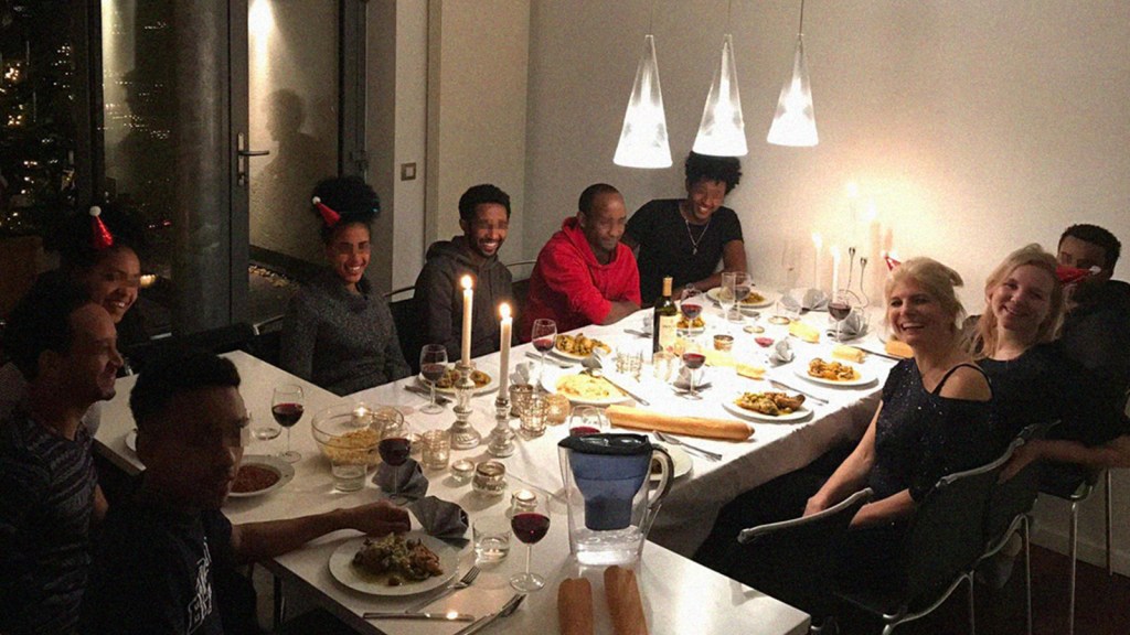 Christel and her two kids, sitting at a table with eight refugees, having dinner together.