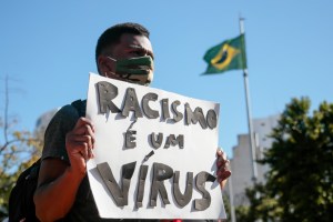 A protestor holds a banner during a protest against Brazilian President Jair Bolsonaro and against racism