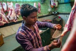 A butcher cuts buffalo meat at a beef store in New Delhi, India