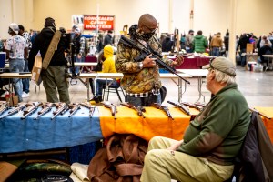 A man, who declined to be identified, shows his gun to an exhibitor at the Pittsburgh Gun Show at the Monroeville Convention Center, Saturday, Feb. 6, 2021, in Monroeville, Pa.