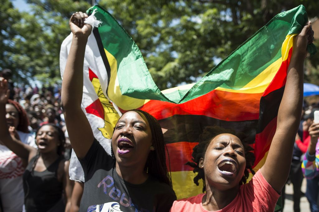 Women holding a flag of Zimbabwe take part in a demonstration of University of Zimbabwe's students, on November 20, 2017​.