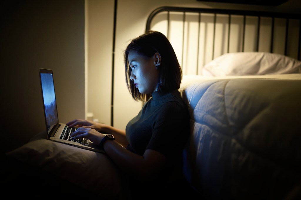 Woman looking a laptop in bed.