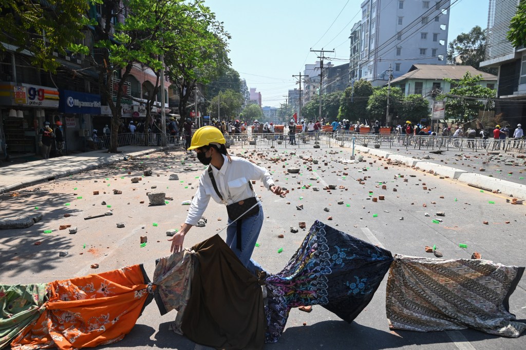 Perempuan membentangkan Longyi, kain tradisional Myanmar, selama demo anti-kudeta