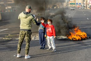 Children pose in front of a burning road block in Lebanon during days-long protests.