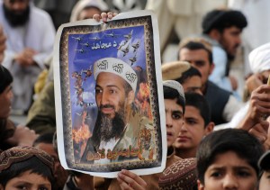 Individuals carry a poster with Osama Bin Laden's face in Pakistan.