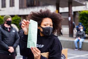 A BLM protester in Belfast, Northern Ireland, holds a fine issued by the Police Service of Northern Ireland during a demonstration. Photo: Conor Kinahan / Alamy Stock Photo