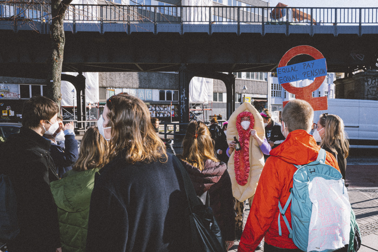 Eine Gruppe Demonstrantinnen mit Plakaten trifft auf eine Gruppe Feministinnen mit Bollerwagen