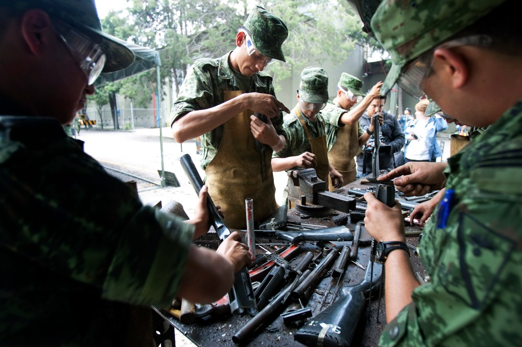 soldiers disassemble guns seized from drug smugglers