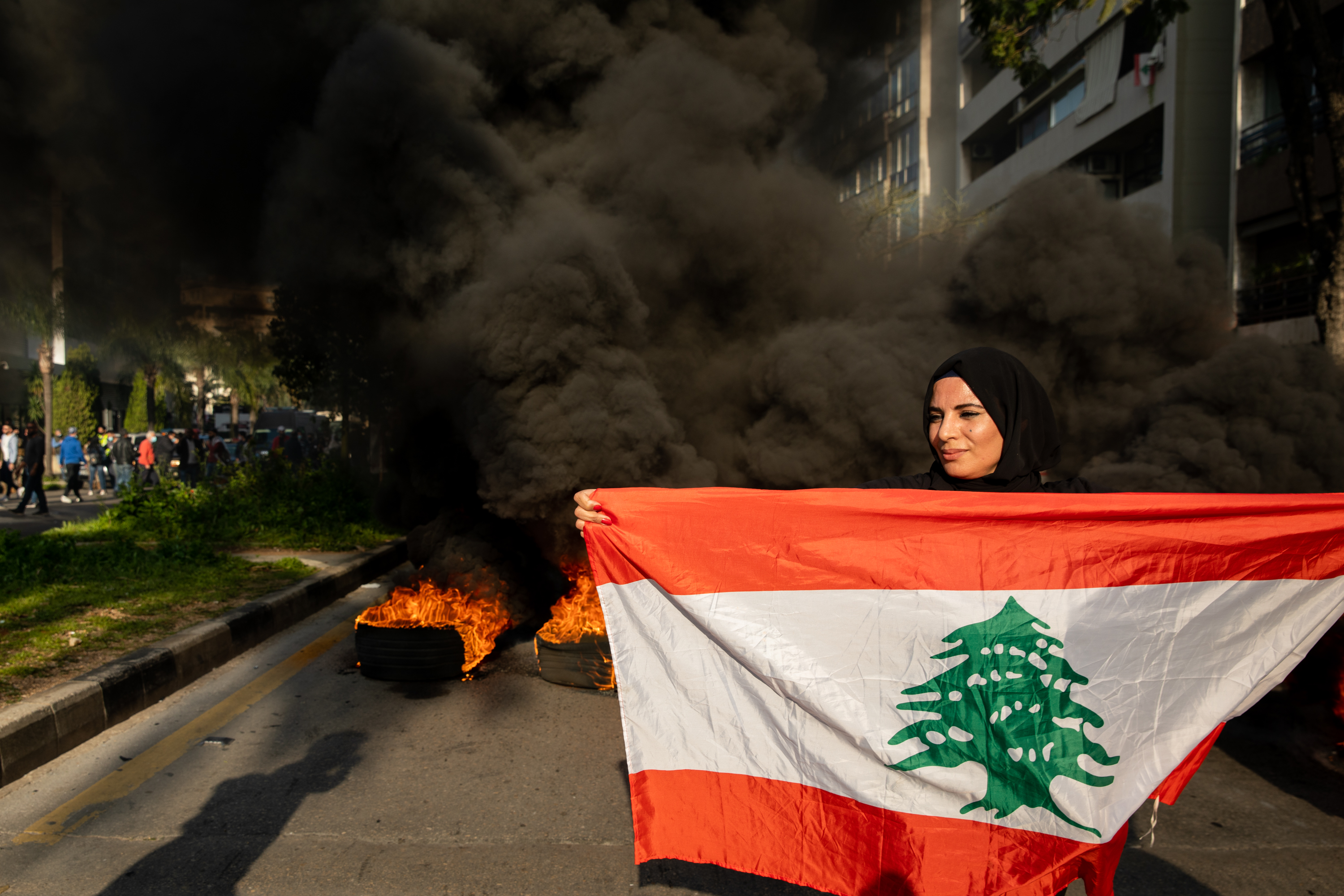 A protester outside the military court holds a Lebanese flag.