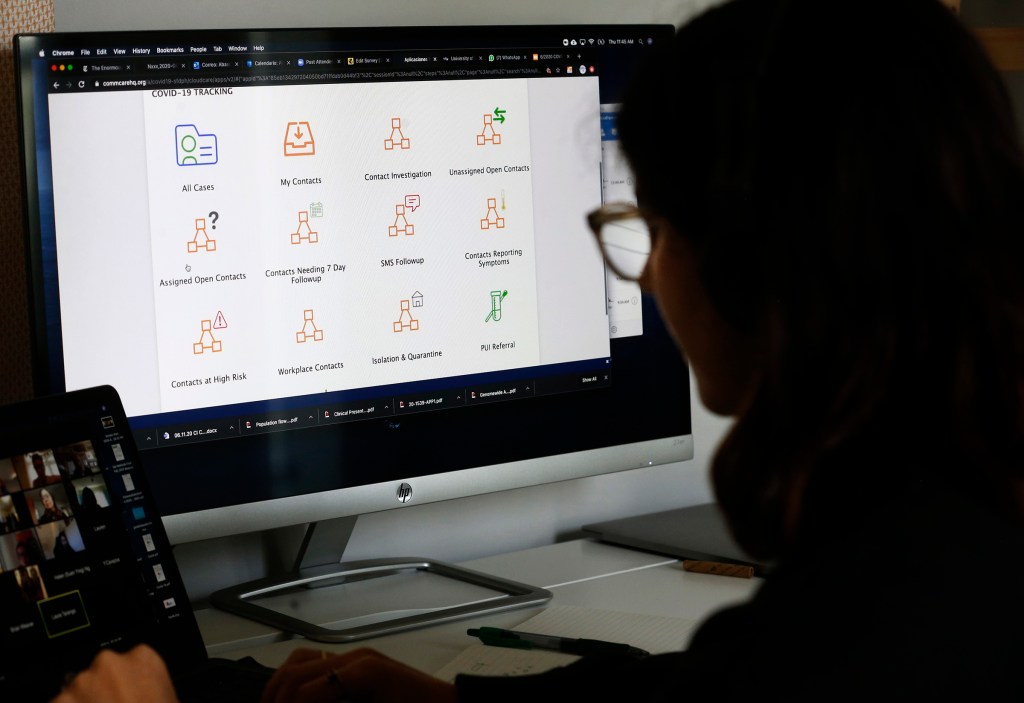 A contact tracer looks at a computer screen while interviewing COVID-19 patients from home.