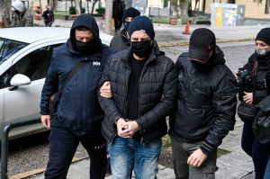 Former artistic director of Greece's national theatre Dimitris Lignadis is escorted handcuffed by police officers to the examining magistrate in Athens