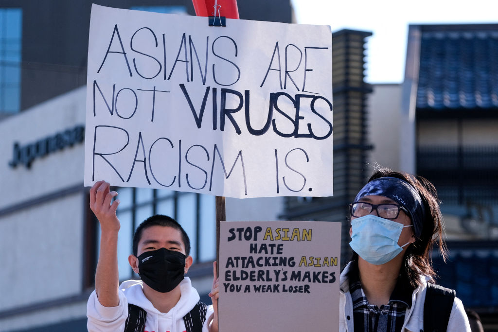 Demonstrators wearing face masks and holding signs take part in a rally