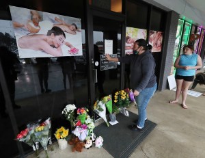 Jessica Lang pauses and places her hand on the door in a moment of grief at Young's Asian Massage parlor where four people were killed, Wednesday, March 17, 2021, in Acworth, Ga.