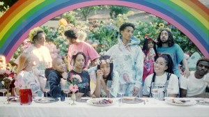 Een groep mensen aan tafel onder een regenboog